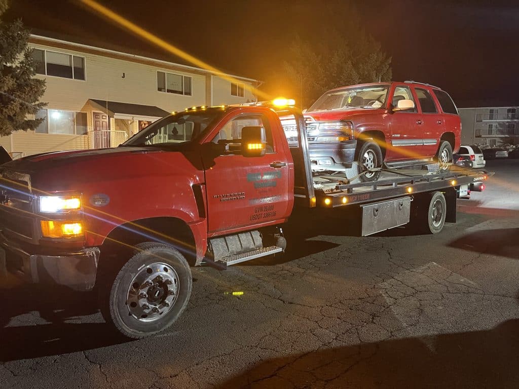 Big Jim's Flat Bed Tow Truck Hauling a Car