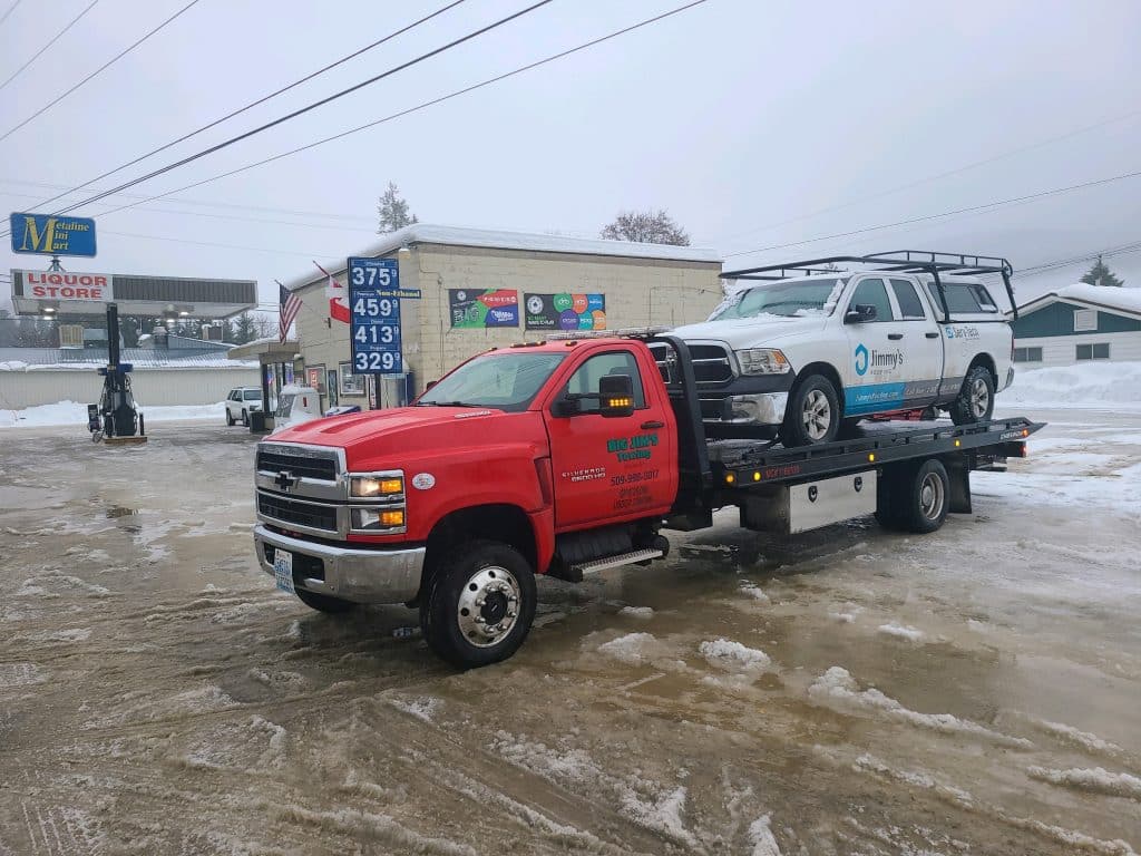 Big jim's Flatbed Tow Truck Hauling a Work Truck
